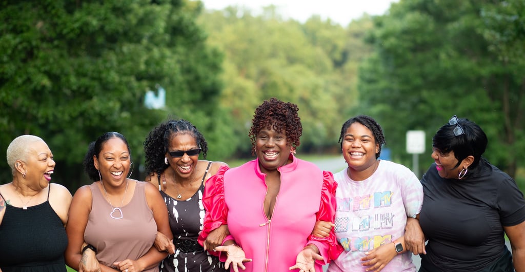 a group of women standing around a woman in a pink dress smiling and looking happy