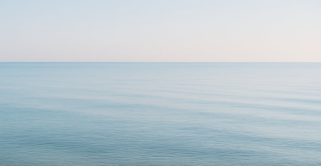 wide shot of a calm sea with empty shoreline, evoking longing and absence.