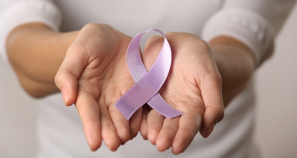 lavender cancer ribbon in woman's hands