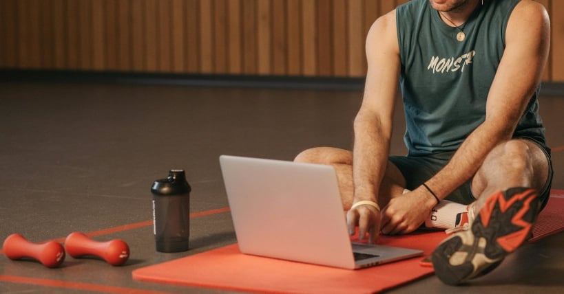 a man sitting on a mat with a laptop computer