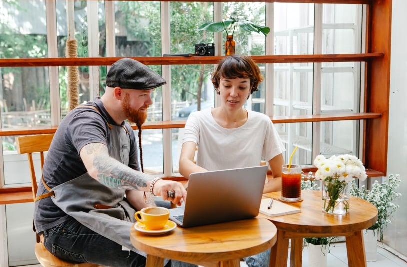 mujer y hombre dueños de restaurante sentados trabajando en su perfil de empresa