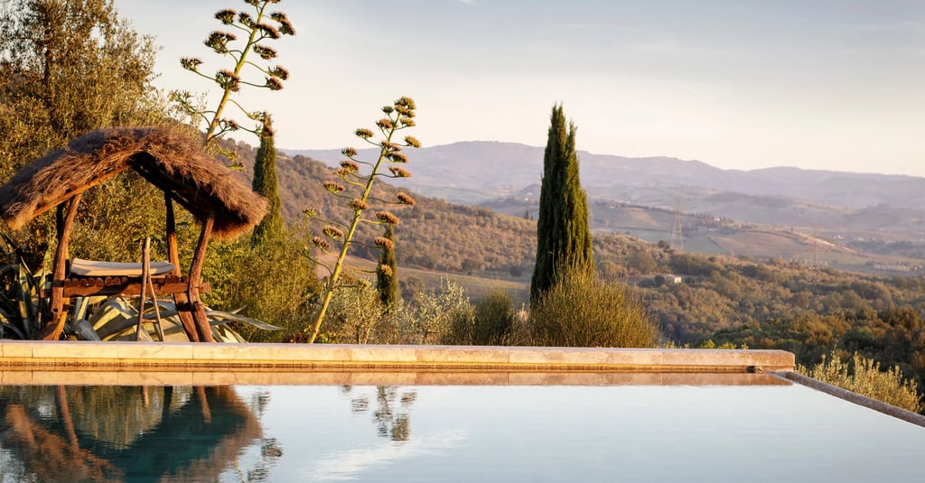 Luxury infinity pool overlooking rolling Tuscan hills and vineyards in Italy at sunset.