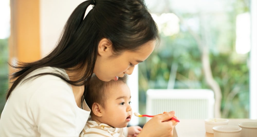 seorang ibu yang sedang menyuapi anaknya
