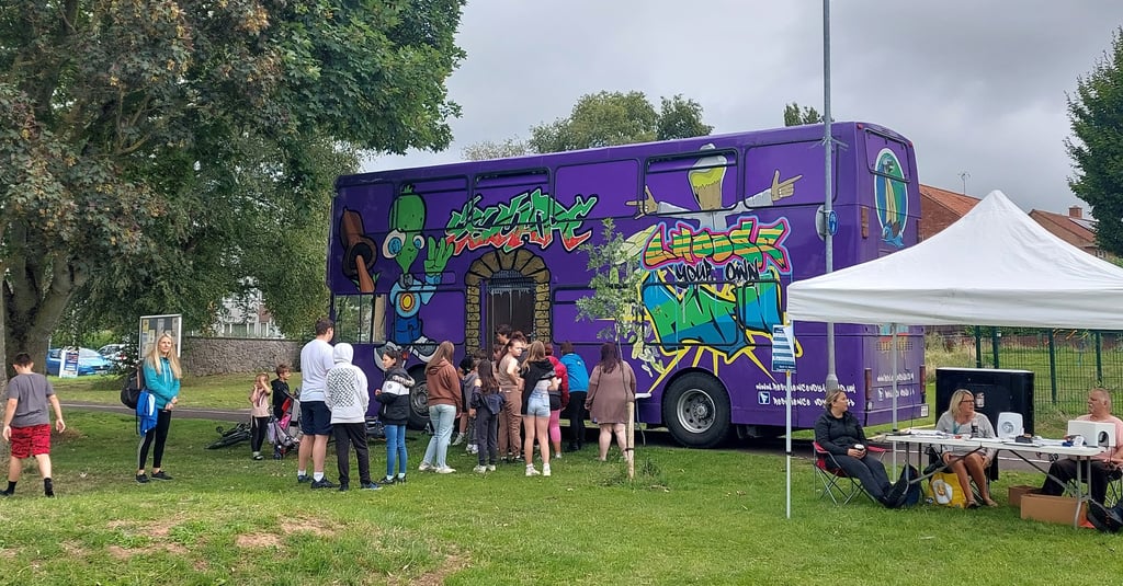 a purple bus parked in a grassy area