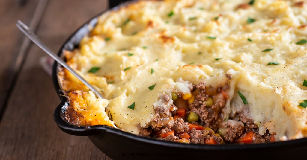Cauliflower mash being spread over ground beef in a skillet for Thrive Shepherd’s Pie