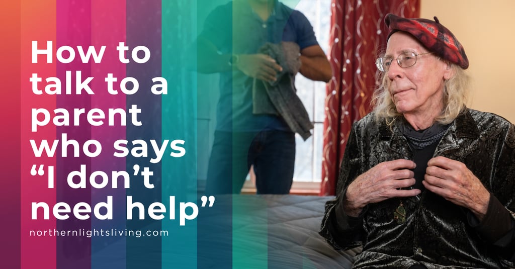 An elderly man wearing a beret sitting on a bed while a caregiver assists her at home.