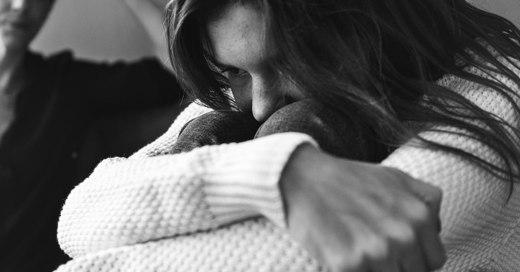 Jeune femme assise, recroquevillée et préoccupée, exprimant un profond malaise émotionnel, avec une