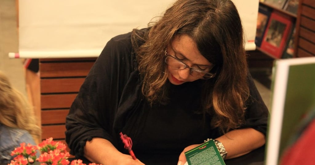a woman is sitting at a table with a book