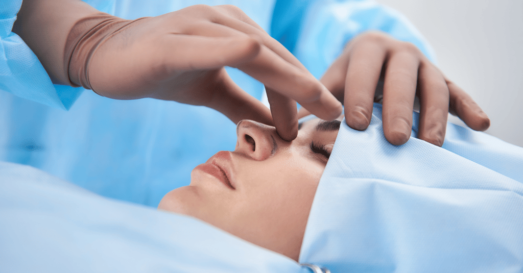 Surgeon performing a rhinoplasty procedure on a patient in a medical clinic for nose reshaping surgery.