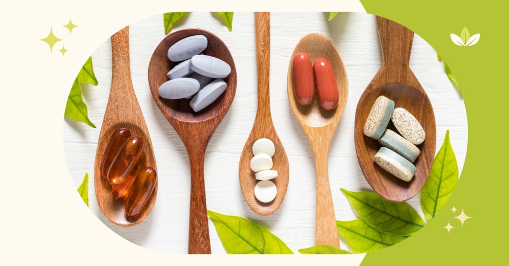 Various dietary supplement capsules and vitamin tablets displayed on wooden spoons with green leaves.