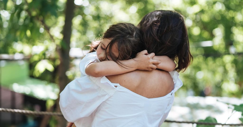 a woman in a white shirt is hugging her daughter