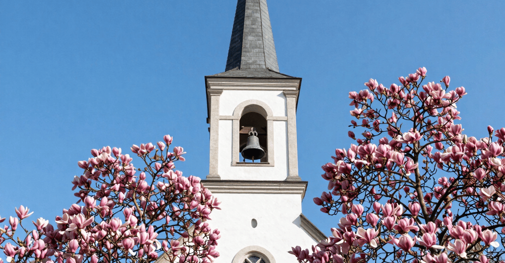 A serene sunrise over a quiet chapel surrounded by trees, symbolizing peace and devotion.