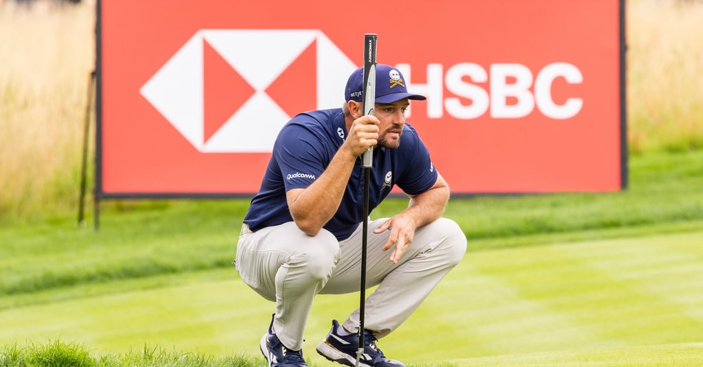 Bryson DeChambeau reads a putt in front of an HSBC sign at a LIV Golf event (Credit: LIV Golf)