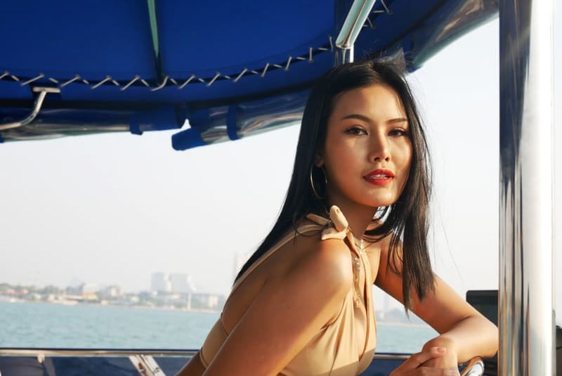 Stilvolle Frau im beigen Badeanzug genießt eine luxuriöse Yachtkreuzfahrt bei Sonnenuntergang