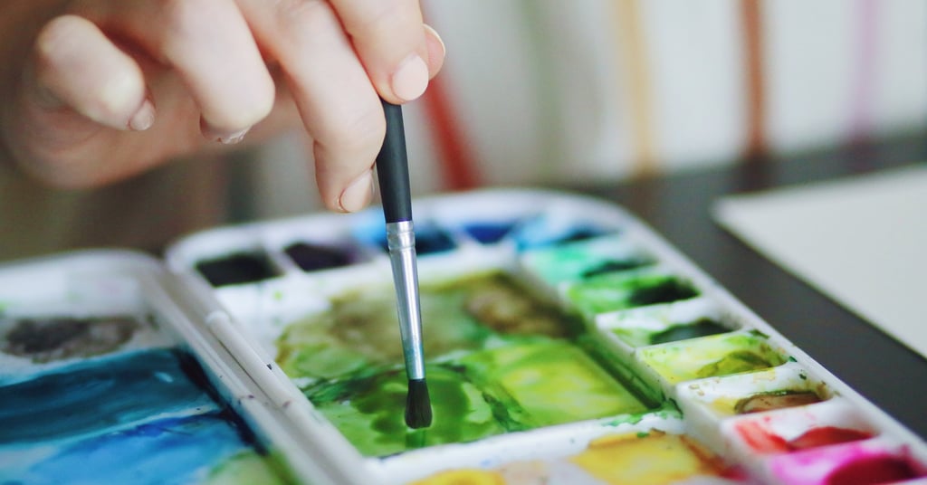 a person holding a paintbrush and painting with a brush