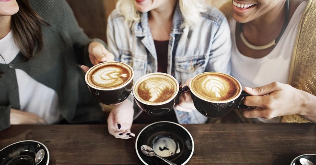 a group of people sitting at a table with coffee cups