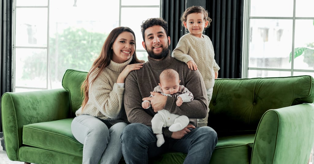 Happy family with two children posing on a green velvet sofa during a home lifestyle photoshoot.