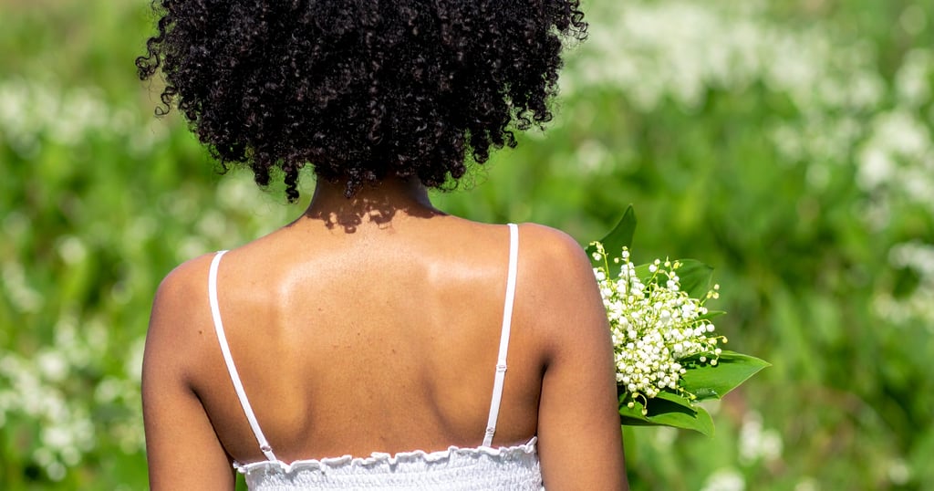 Black woman holding lily of the valley flowers