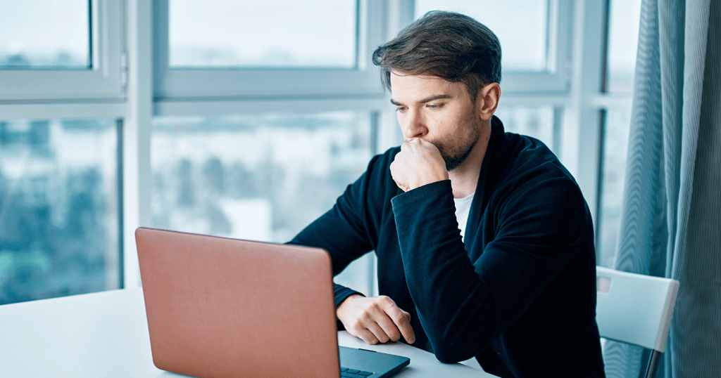 a man sitting at a table with a laptop computer