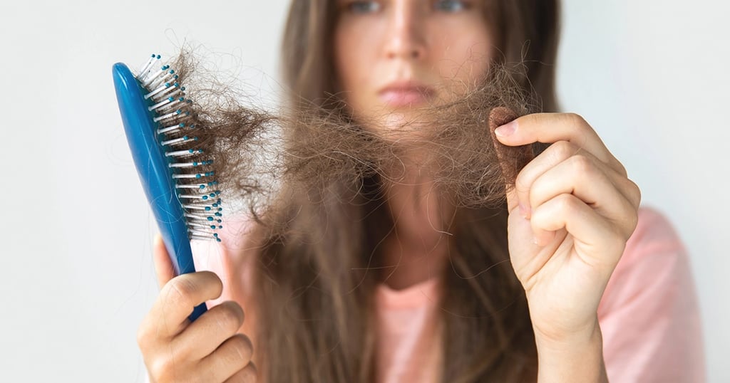 Mujer sosteniendo cepillo con cabellos caído