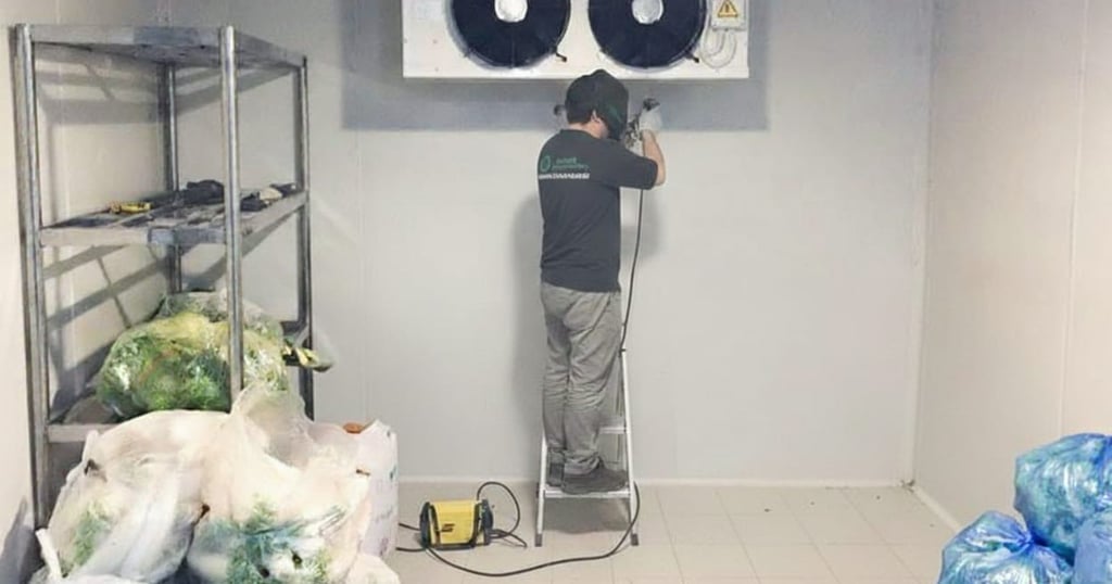 Técnico realizando reparo em evaporador de câmara fria comercial.