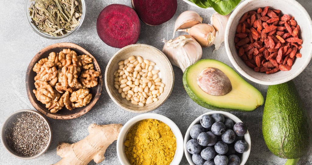 Flat lay of healthy superfoods including avocado, blueberries, walnuts, chia seeds, and turmeric powder.