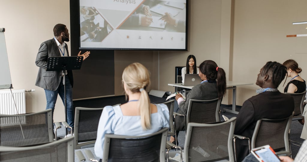 a man in a suit and tie is doing a presentation while others sitting and listening