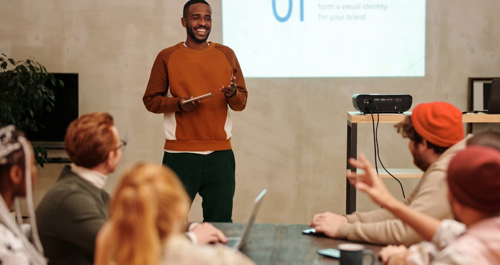 a man standing in front of a presentation on a projector to a group of people sitting and watching