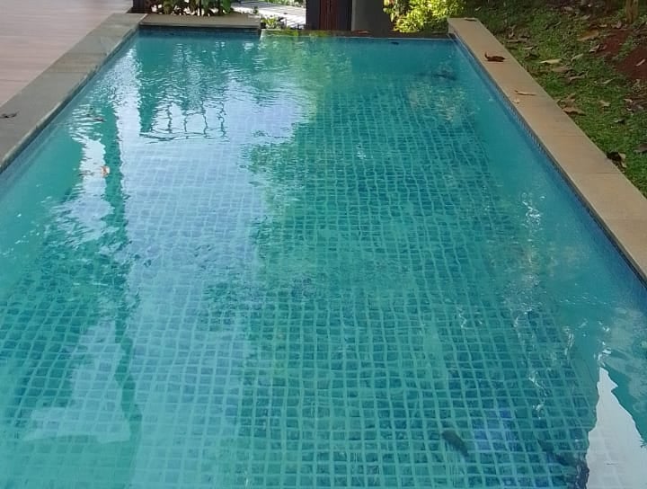 Suasana malam kolam renang air hangat di villa Karawang, lampu menyala.