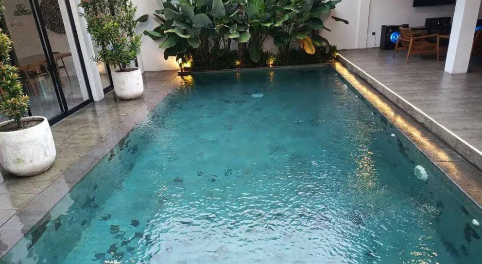 kolam renang minimalis di halamn belakang rumah dengan finishing batu alam