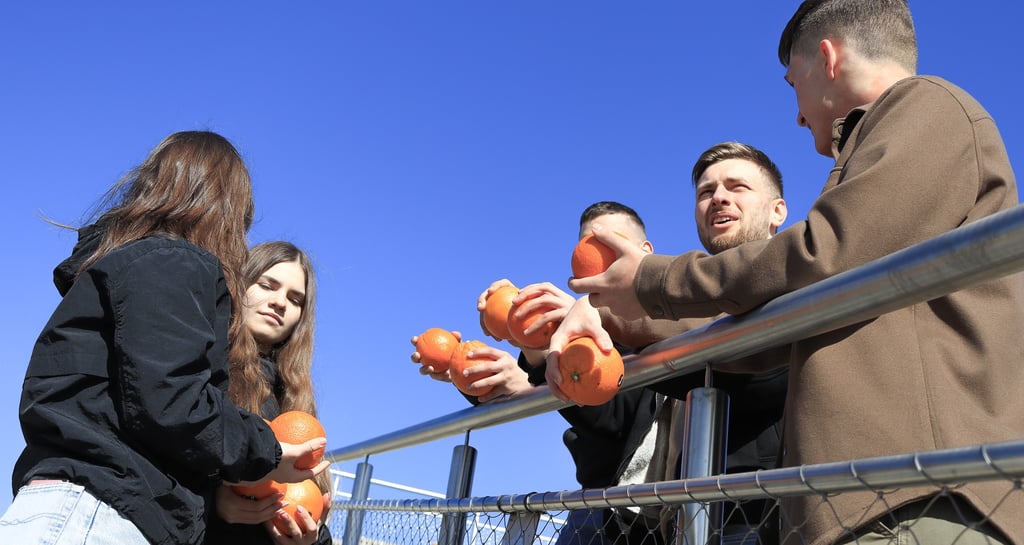 jauni zmones lauke sneka ir rankose laiko apelsinus