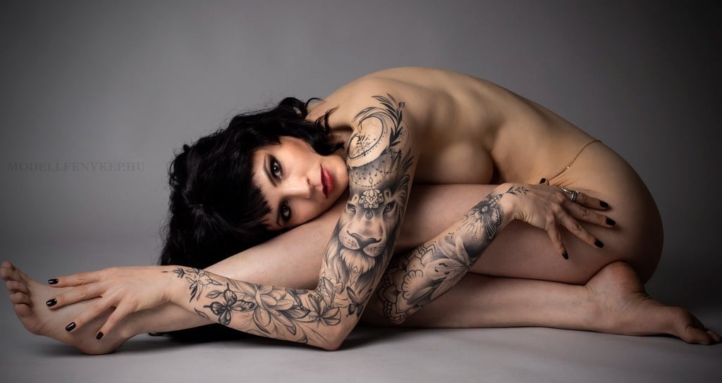 a beautiful woman with tattoos on her arm and arms implied nude glamour
