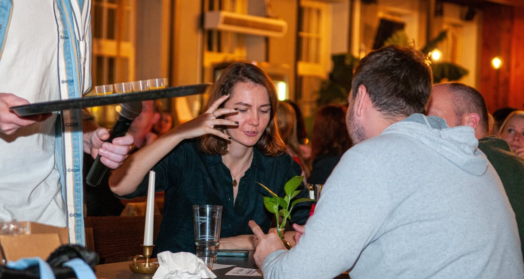 a man and woman sitting at a table with a waiter