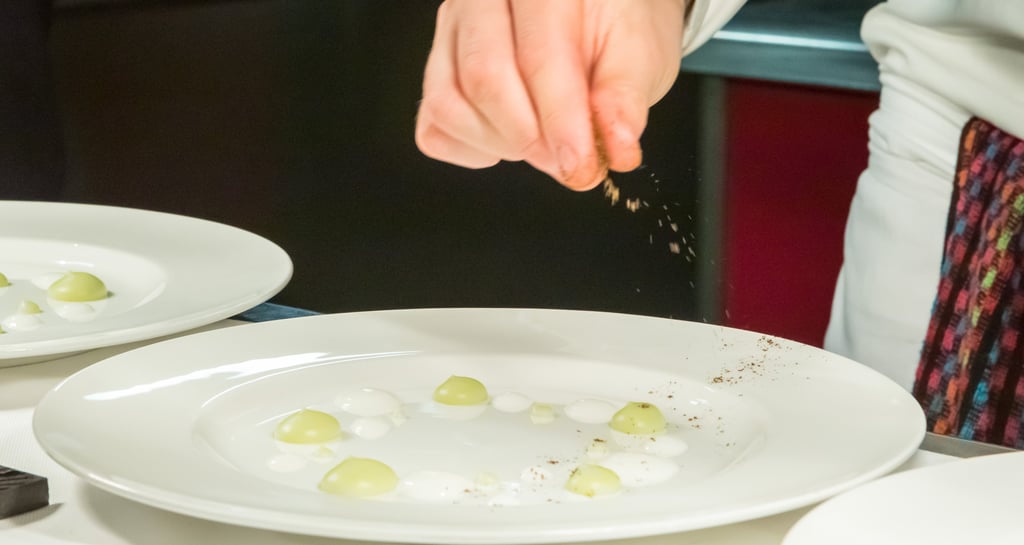 uno chef che condisce il suo piatto