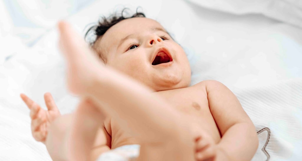 Smiling baby lying on bed – natural newborn photography by Fred Art Studio London