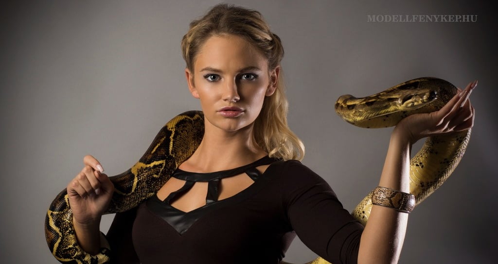 beautiful woman model holding a big snake on a photoshoot