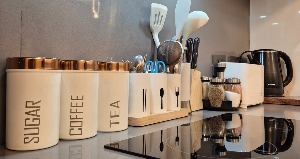 a kitchen counter top with a stove top, and other kitchen amenities like spoons, spatula, containers
