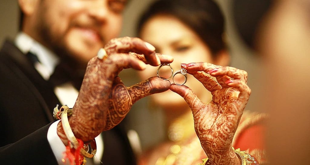 Bride and groom holding the wedding ring