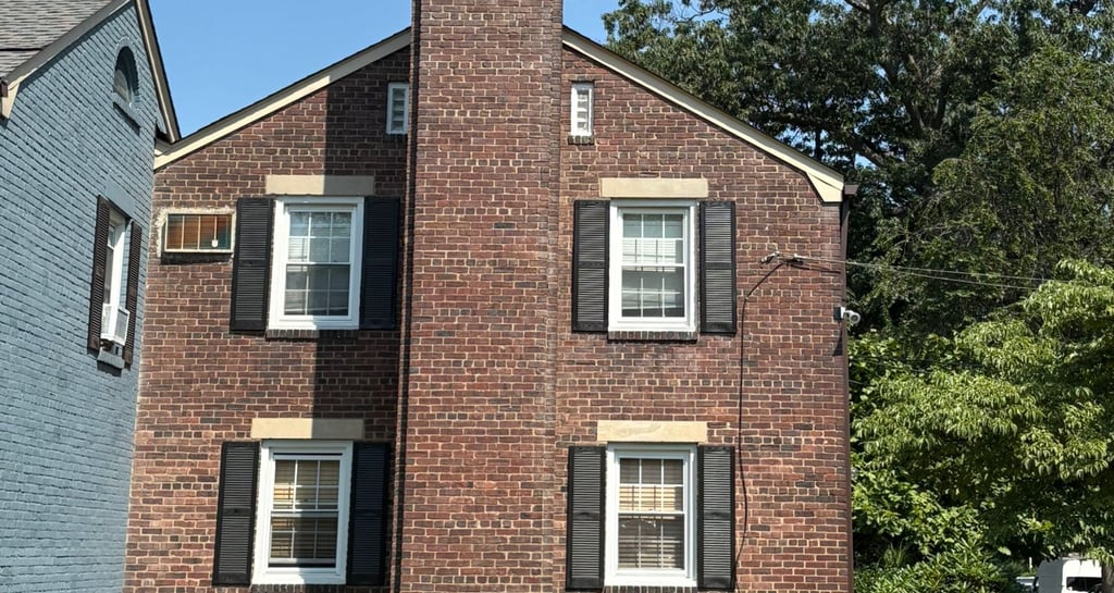 A tall, outdoor brick chimney on a house in Roslyn, New York, undergoing inspection for a major rebuild and repair project by
