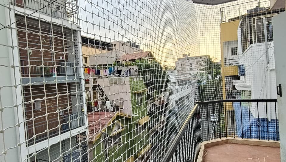 Close-up of a securely fastened balcony safety net against a Basavanagudi apartment backdrop.