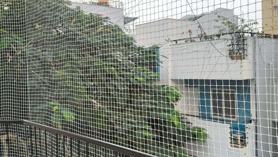 Evening view of a balcony with safety netting softly illuminated by warm indoor lights.