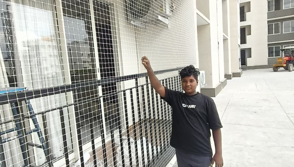 Wide shot of a residential balcony fully covered with a sturdy safety net, sunlight filtering throug