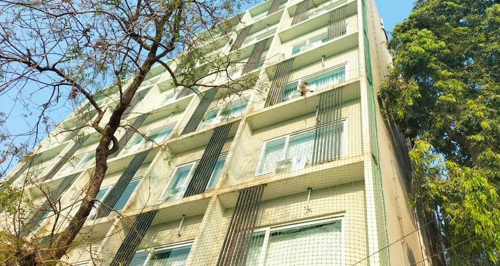 Safety nets stretched tightly around scaffolding with the Bengaluru skyline in the background.