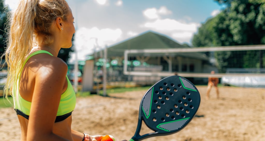 Atleta de beach tennis se preparando para fazer seu serviço no jogo.