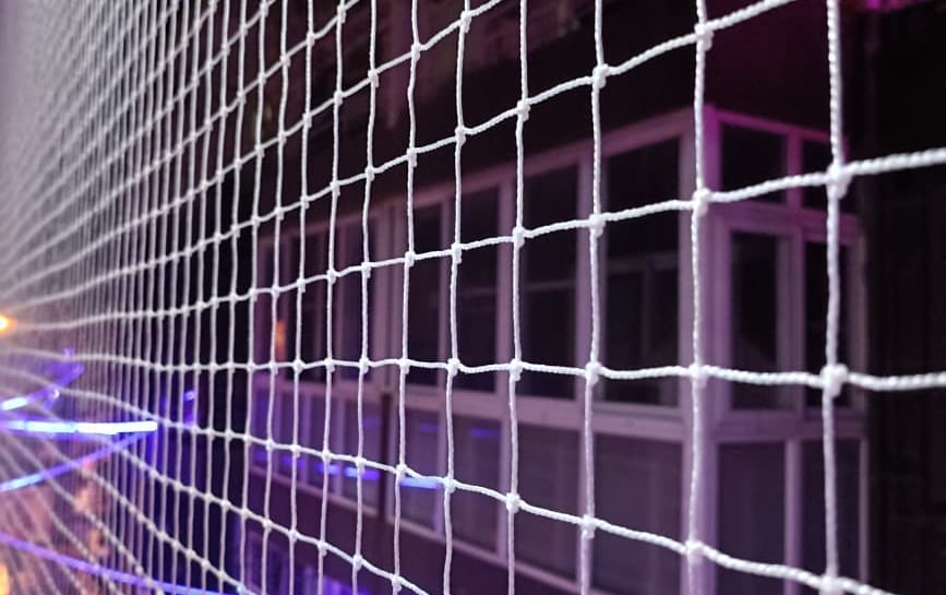 Close-up of a sturdy pigeon net securely fitted on a balcony railing in Bellandur.