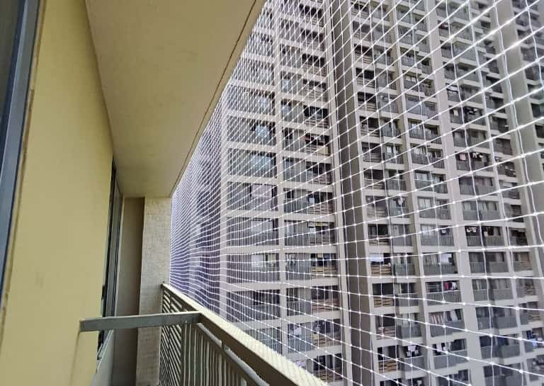 Technician from Arjilli Enterprises installing pigeon nets on a residential balcony.