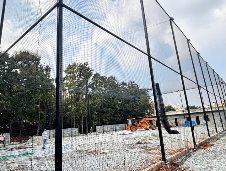 Evening view of a volleyball court with neatly installed protective nets glowing under floodlights.