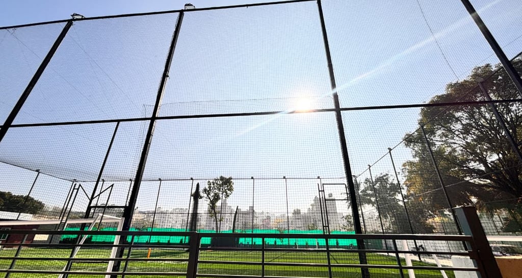 Evening view of a basketball court with new netting glowing under floodlights.