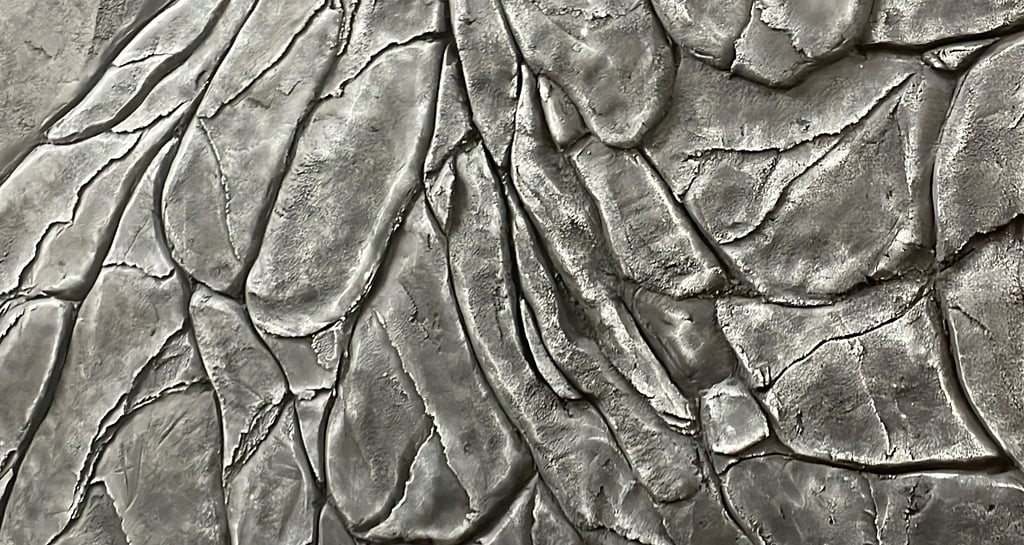 Textured decorative concrete wall with a realistic dark grey faux stone and rock cliff face finish.