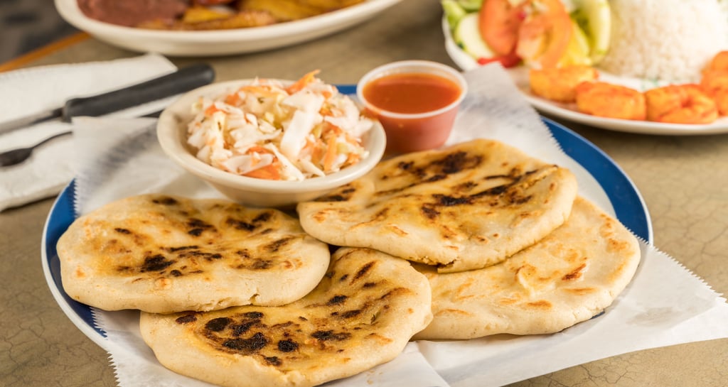 a plate of pupusas with a bowl of cultido and a bowl of salad